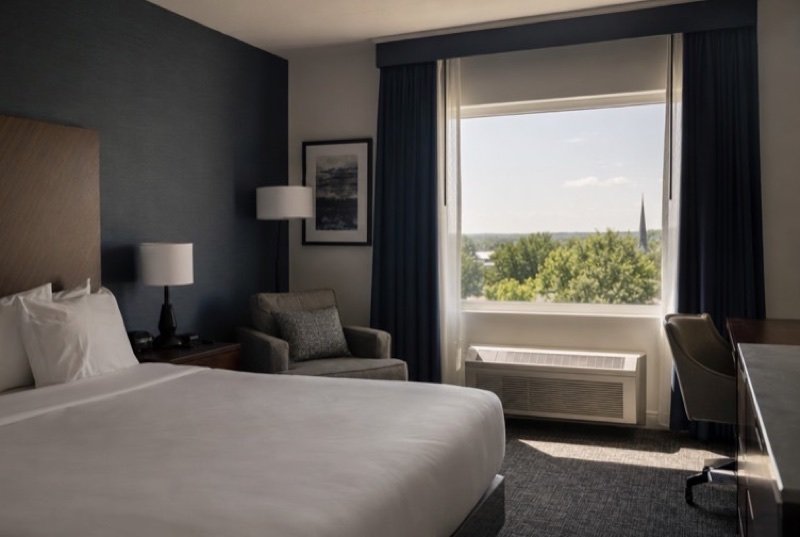 Quiet guest room with a made king bed, a reading chair and morning sun, the core product of the hotel industry