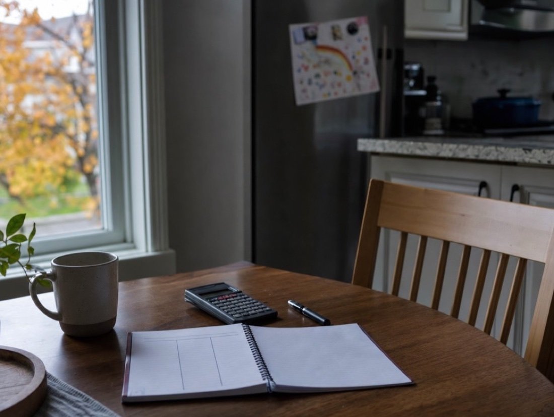 Kitchen table set with a notebook and a calculator for working out a monthly budget