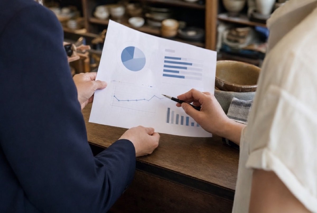 Owner and advisor side by side at a shop counter, going over printed pages